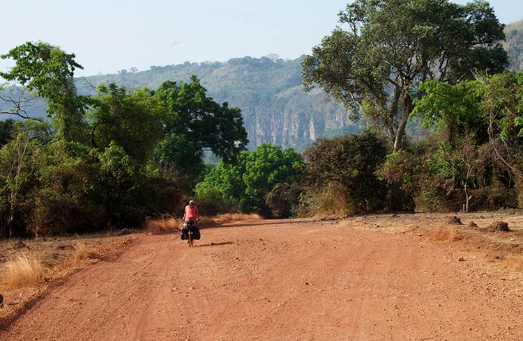 A man riding a bike on a dirt road in Kindia, Guinea, West Africa