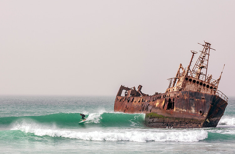A surfer next to the shipwreck graveyard in Nouadhibou