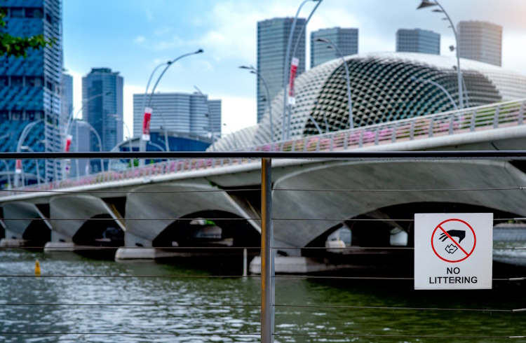 A no-littering sign beside a river in downtown Singapore.