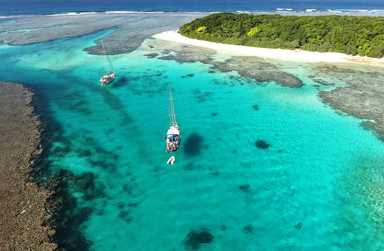 Sailing boats anchored off of the Robinson Crusoe Island Manihiki in Tonga's Vav'u Island group
