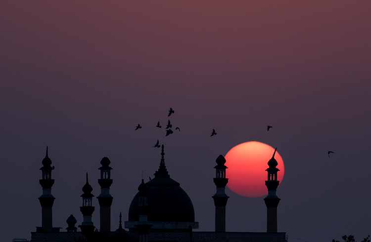 Sunset behind the Mosque Minar and the flying birds in Karachi