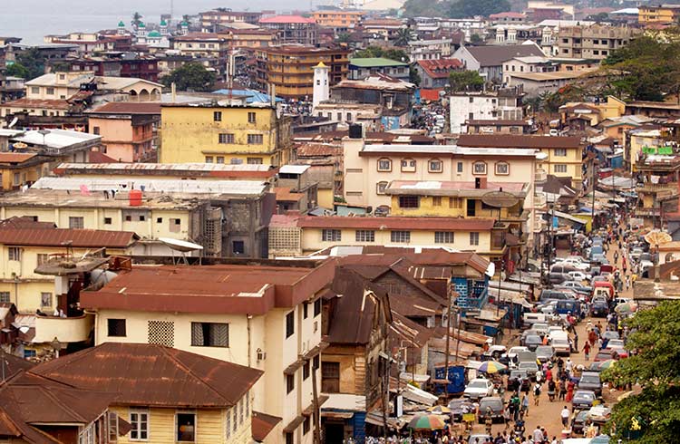 Looking out over brown and red buildings to see crowded streets of Sierra Leone below