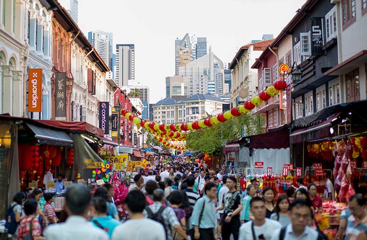 Crowded streets of Chinatown in Singapore, with tall buildings in the background