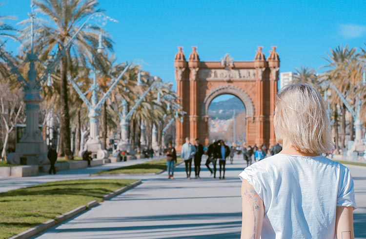 A woman stands in front of Arc de Triomf in Barcelona, Spain