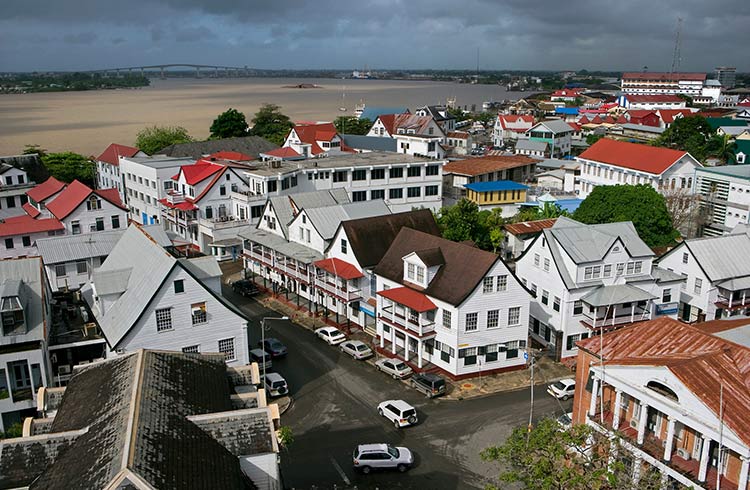 View of buildings from above, beside a murky brown river in Suriname