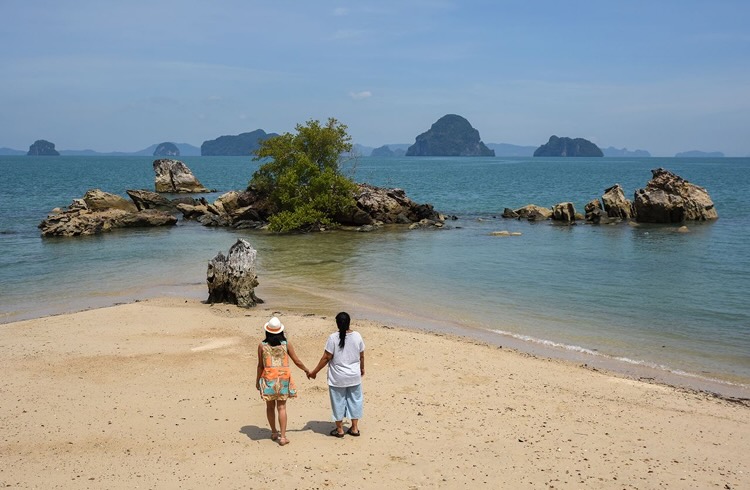 A couple walking hand in hand on a beach in Thailand