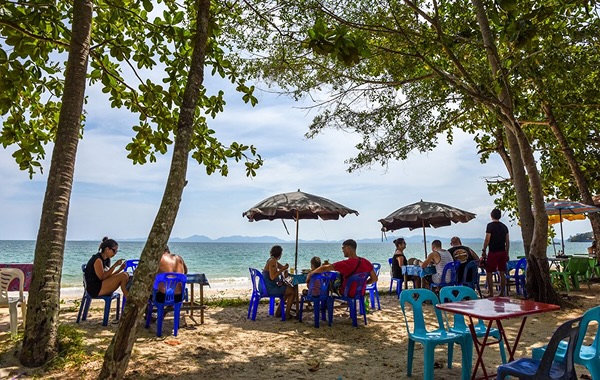 A Thailand beach with people sitting on tables