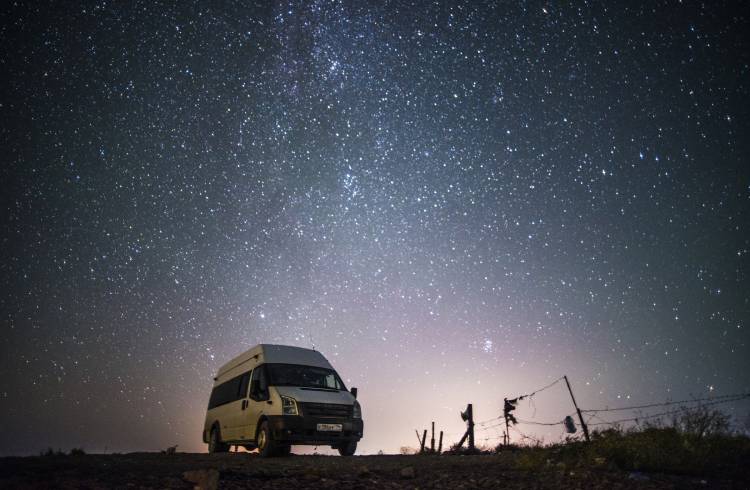 A campervan parked under a starry sky.