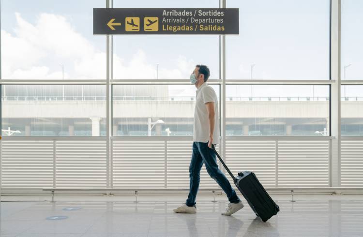 A man walks through an airport wearing a face mask to prevent the spread of COVID-19.