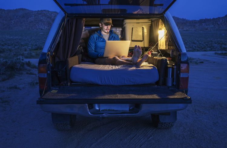A digital nomad working from the back of his car