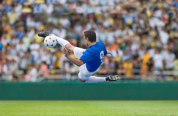 Male soccer player kicking ball in stadium