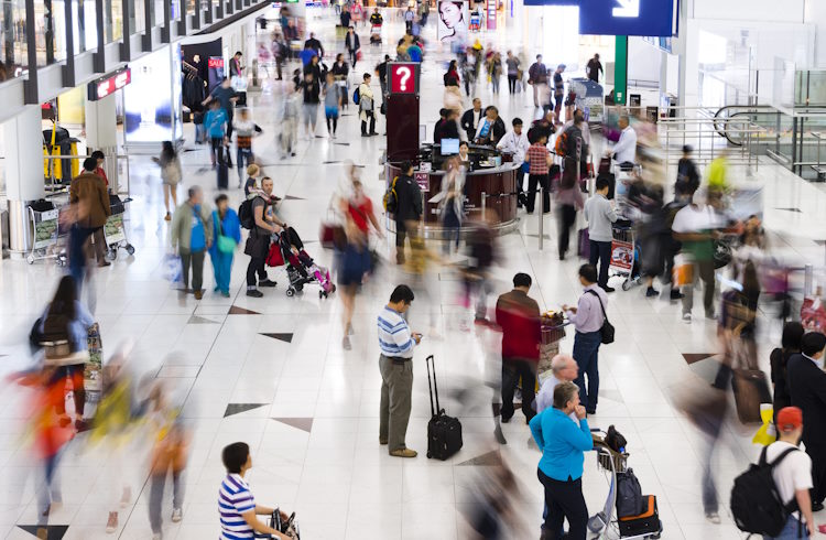 Passengers rush through a busy airport terminal.