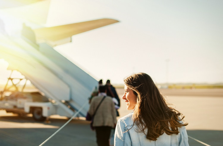 A woman walks across an airport tarmac towards the plane she's about to board.
