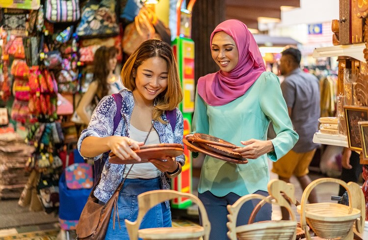 Two smiling women looking at wares at a market