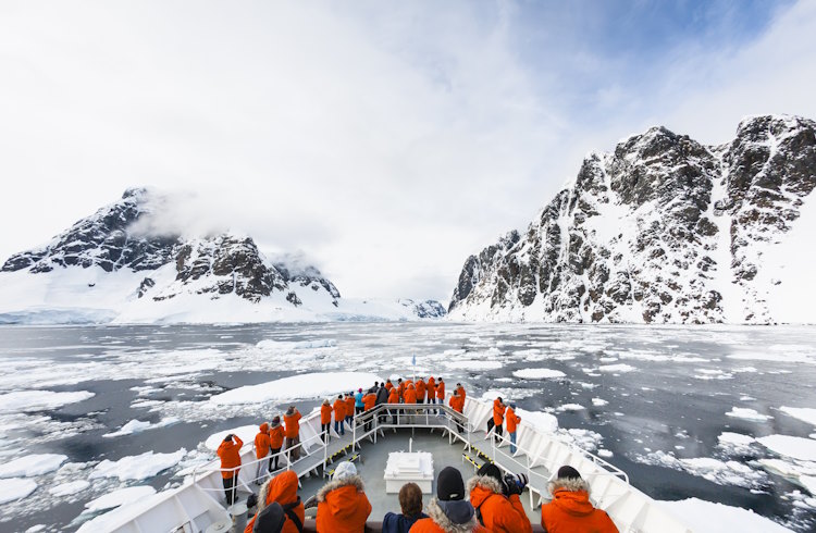 Travelers stand on the deck of an expedition cruise ship in Antarctica.