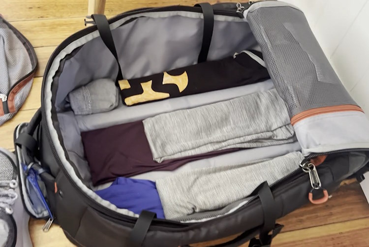 A open suitcase with workout clothes filling the gaps between the handle rails.