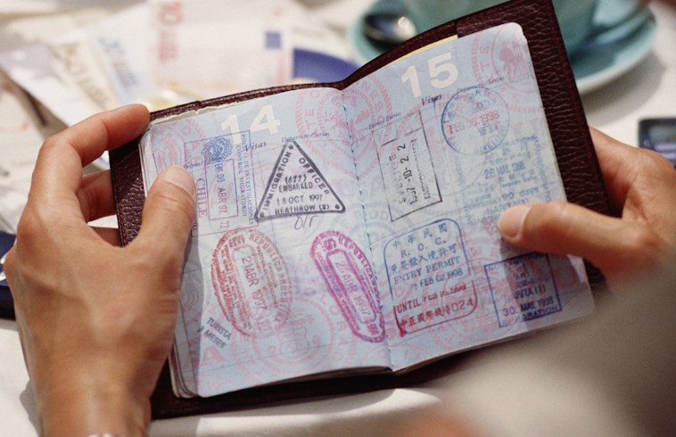 A man holds a passport open to a page filled with stamps.