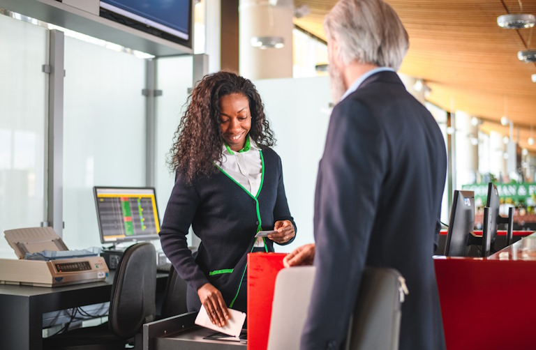 An employee scans a boarding pass while checking ID at an airport gate.