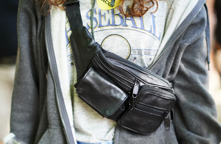 A traveler wears a belt bag across her body.