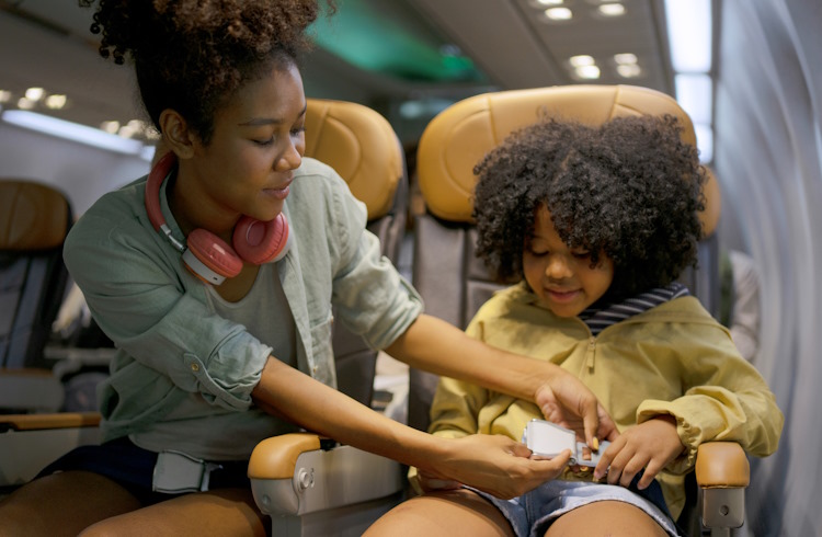 A mother helps her child with his seatbelt on a commercial airplane.