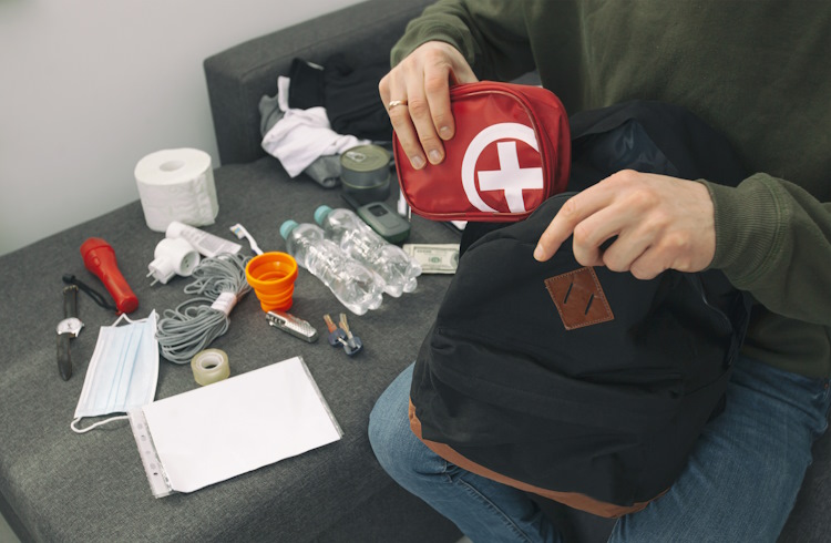 A man fills his backpack with a first-aid kit and other safety supplies.