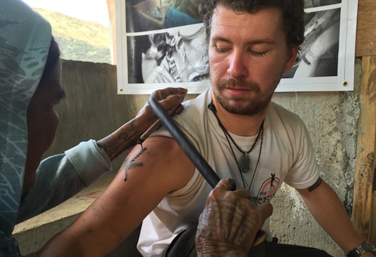 A traveler receives a bamboo tap tattoo in the Philippines.