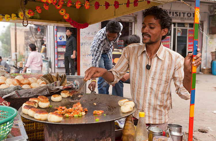 "Check the seals on bottles, wash your hands, and only eat steaming hot food that’s cooked in front of you." A vendor cooking street food from his cart in Amber, Rajasthan