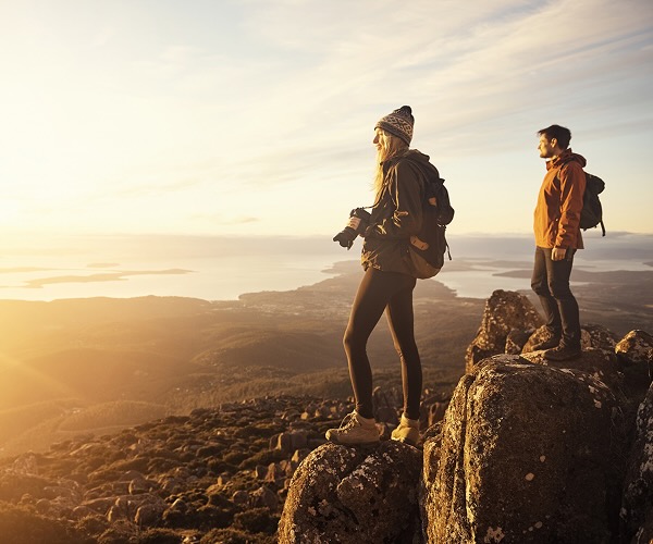 Shot of a young couple taking pictures from the top of a mountain
